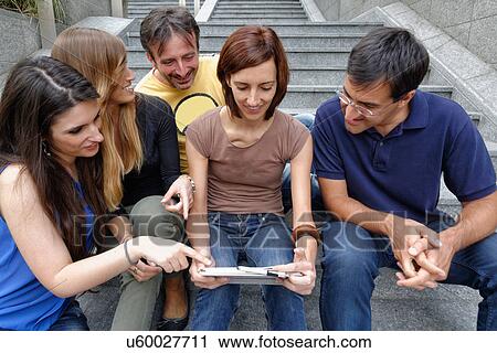 Stock Image - Group of friends looking at digital tablet. Fotosearch