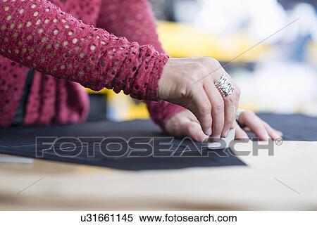 Hands of mature seamstress chalking outline onto textile on work table View Large Photo Image Stock Photography - Hands of mature seamstress chalking outline onto textile on work table. Fotosearch