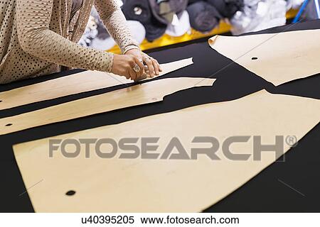 Stock Photography - Hands of mature seamstress chalking shape onto textile on work table. Fotosearch