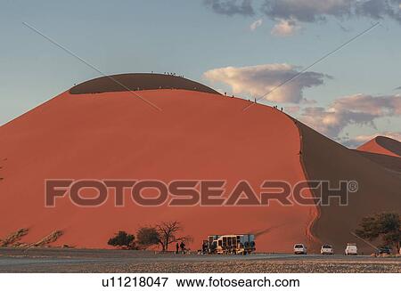 Large group of tourists climbing giant sand dune, Sossusvlei National Park, Namibia View Large Photo Image Stock Photo - Large group of tourists climbing giant sand dune, Sossusvlei National Park, Namibia. Fotosearch