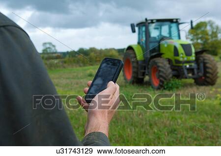 Male farmers hand holding up smartphone in field View Large Photo Image Stock Photo - Male farmers hand holding up smartphone in field. Fotosearch