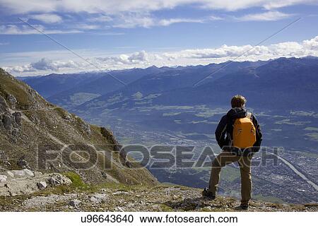 Male hiker on top of mountain looking down at valley, Innsbruck Tyrol, Austria View Large Photo Image Stock Image - Male hiker on top of mountain looking down at valley, Innsbruck Tyrol, Austria. Fotosearch