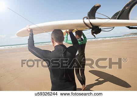 Man and teenage boy carrying surfboards on beach View Large Photo Image Picture - Man and teenage boy carrying surfboards on beach. Fotosearch