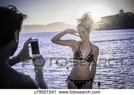 Stock Image - Man photographing young woman on vacation. Fotosearch
