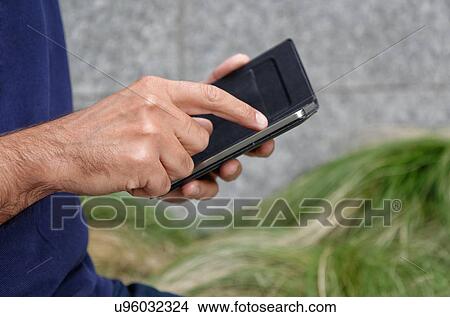 Picture - Man using smartphone, focus on smartphone. Fotosearch