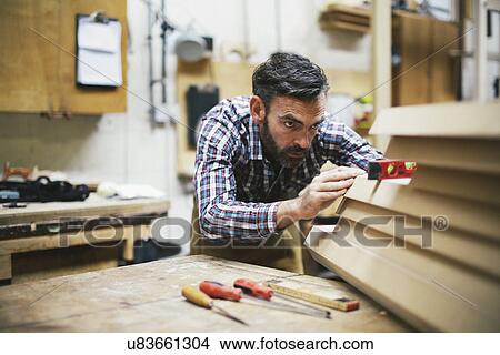 Picture - Mature craftsman using spirit level in pipe organ workshop. Fotosearch