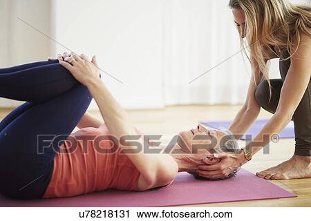 Mature female student lying on back holding knees in pilates class View Large Photo Image Stock Image - Mature female student lying on back holding knees in pilates class. Fotosearch