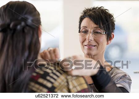 Stock Image - Mature seamstress adjusting shoulder of customers dress in workshop. Fotosearch
