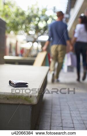 Mid adult couple walking with shopping bags, wallet left on seat behind them View Large Photo Image Picture - Mid adult couple walking with shopping bags, wallet left on seat behind them. Fotosearch
