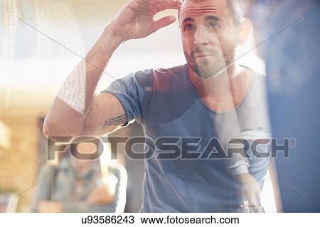 Stock Image - Mid adult man looking in shop window. Fotosearch