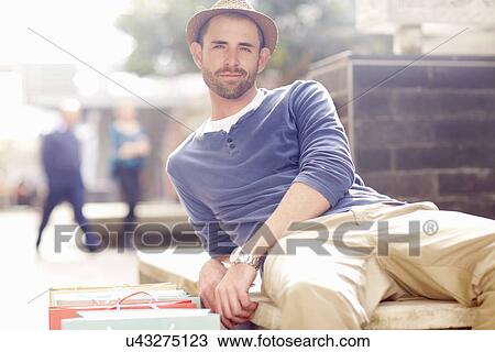 Mid adult man relaxing on seat, shopping bags beside him View Large Photo Image Stock Image - Mid adult man relaxing on seat, shopping bags beside him. Fotosearch