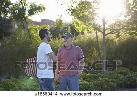 Picture - Mid adult man talking to senior man. Fotosearch