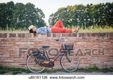 Mid adult woman lying on brick wall, Tuscany, Italy View Large Photo Image Stock Photograph - Mid adult woman lying on brick wall, Tuscany, Italy. Fotosearch