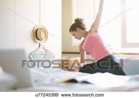 Stock Photo - Mid adult woman practicing yoga in bedroom. Fotosearch