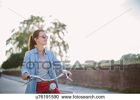 Mid adult woman pushing bicycle on rural road, Tuscany, Italy View Large Photo Image Stock Image - Mid adult woman pushing bicycle on rural road, Tuscany, Italy. Fotosearch