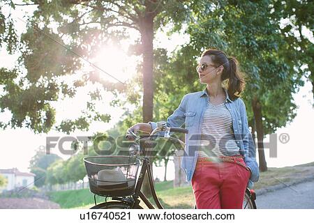 Mid adult woman pushing bicycle, Tuscany, Italy View Large Photo Image Stock Image - Mid adult woman pushing bicycle, Tuscany, Italy. Fotosearch