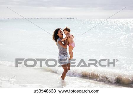 Stock Image - Mother and toddler daughter paddling in sea, Tuscany, Italy. Fotosearch