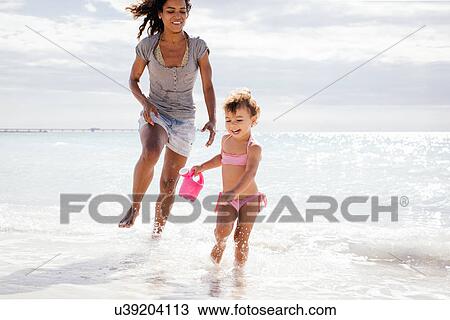 Mother and toddler daughter running with toy watering can on beach, Tuscany, Italy View Large Photo Image Stock Image - Mother and toddler daughter running with toy watering can on beach, Tuscany, Italy. Fotosearch