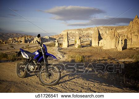 Stock Image - Motorcycle parked in front of pinnacle rock formations, Cappadocia, Anatolia, Turkey. Fotosearch