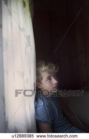 Pensive teenage boy by curtains View Large Photo Image Stock Photography - Pensive teenage boy by curtains. Fotosearch