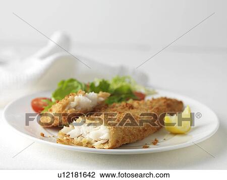 Stock Image - Plate of battered cod with green salad, cherry tomatoes and lemon slice. Fotosearch