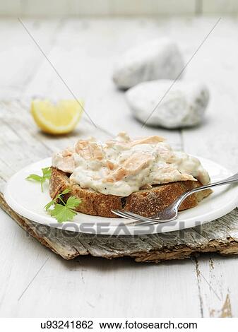 Stock Image - Poached & smoked salmon cocktail and dill sauce on bread with coriander garnish. Fotosearch