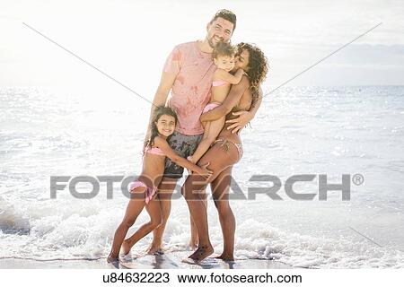 Stock Image - Portrait of couple with two girls on beach, Tuscany, Italy. Fotosearch