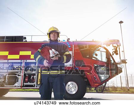 Stock Photo - Portrait of fireman in front of fire engine in airport fire station. Fotosearch