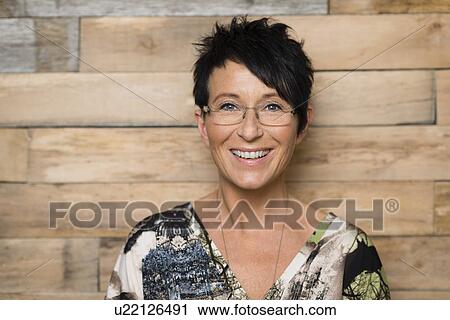 Stock Image - Portrait of mature seamstress in front of workshop wall. Fotosearch