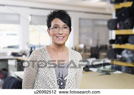 Stock Image - Portrait of mature seamstress in workshop. Fotosearch