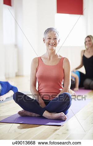 Portrait of mature woman sitting cross legged in pilates class View Large Photo Image Stock Photo - Portrait of mature woman sitting cross legged in pilates class. Fotosearch