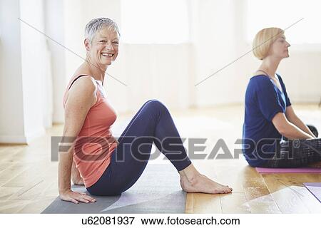 Stock Photo - Portrait of mature woman sitting on floor in pilates class. Fotosearch