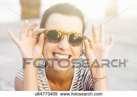 Portrait of mid adult woman holding sunglasses, Tuscany, Italy View Large Photo Image Stock Photography - Portrait of mid adult woman holding sunglasses, Tuscany, Italy. Fotosearch