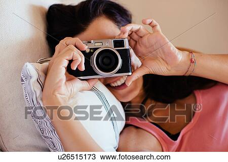 Portrait of mid adult woman lying on bed holding up digital SLR camera View Large Photo Image Stock Image - Portrait of mid adult woman lying on bed holding up digital SLR camera. Fotosearch