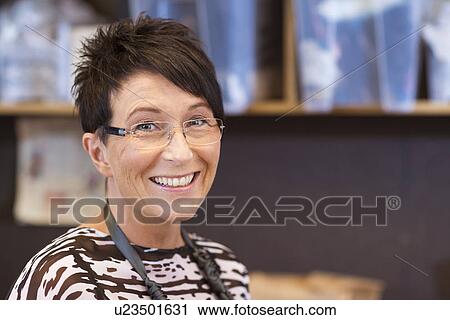 Stock Image - Portrait of smiling mature seamstress in workshop. Fotosearch