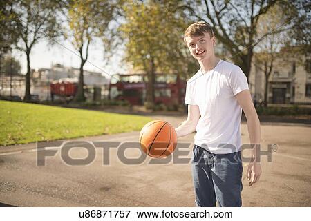 Portrait of smiling young male basketball player holding basketball View Large Photo Image Stock Photo - Portrait of smiling young male basketball player holding basketball. Fotosearch
