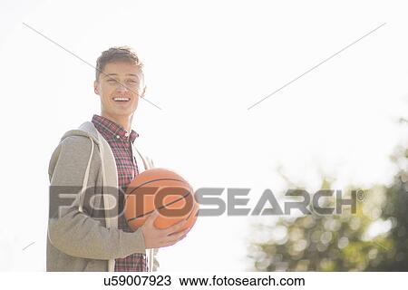 Portrait of smiling young man holding basketball View Large Photo Image Stock Image - Portrait of smiling young man holding basketball. Fotosearch