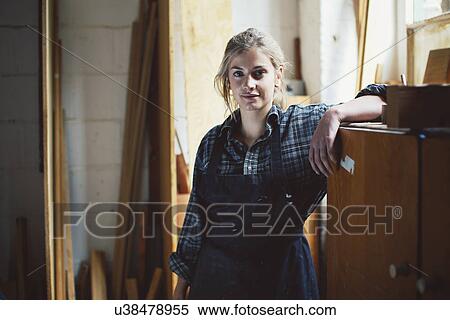 Stock Photography - Portrait of young craftswoman leaning on cupboard in organ workshop. Fotosearch