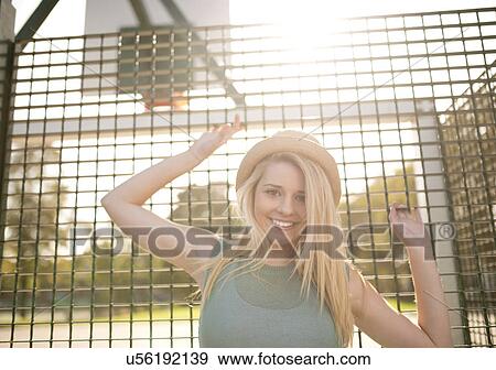 Portrait of young female basketball player holding onto wire fence View Large Photo Image Stock Photo - Portrait of young female basketball player holding onto wire fence. Fotosearch