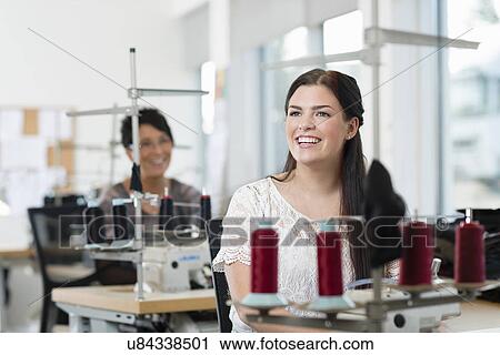 Stock Image - Portrait of young seamstress using sewing machine in workshop. Fotosearch