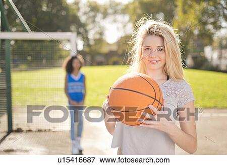 Portrait of young woman holding up basketball View Large Photo Image Stock Photo - Portrait of young woman holding up basketball. Fotosearch