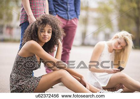 Stock Photograph - Portrait of young woman in park with friends. Fotosearch