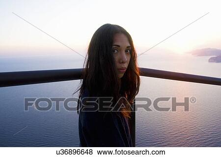 Stock Photo - Portrait of young woman looking over her shoulder at coast, Marseille, France. Fotosearch