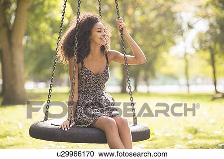 Portrait of young woman sitting on tire swing View Large Photo Image Stock Image - Portrait of young woman sitting on tire swing. Fotosearch