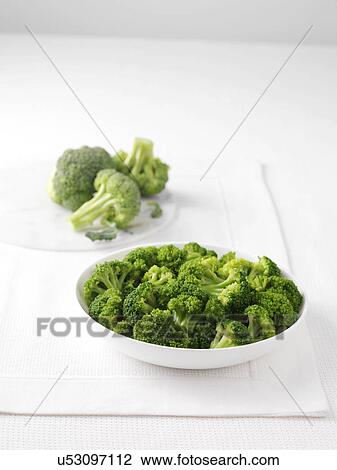 Stock Image - Raw broccoli on marble cutting board and bowl of boiled broccoli. Fotosearch