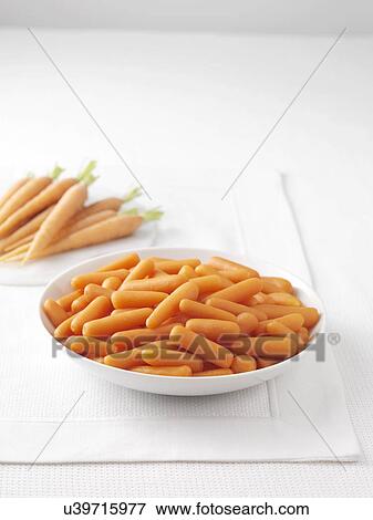 Stock Photo - Raw carrots on marble cutting board and bowl of boiled carrots. Fotosearch