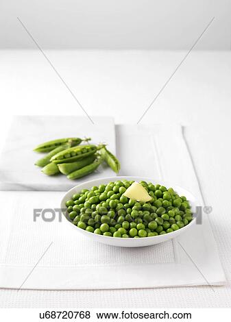 Stock Photo - Raw pea pods on marble cutting board and bowl of boiled peas with butter. Fotosearch