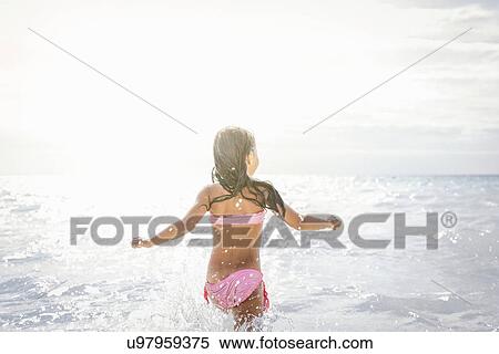 Rear view of girl running and splashing in sea, Tuscany, Italy View Large Photo Image Stock Photography - Rear view of girl running and splashing in sea, Tuscany, Italy. Fotosearch