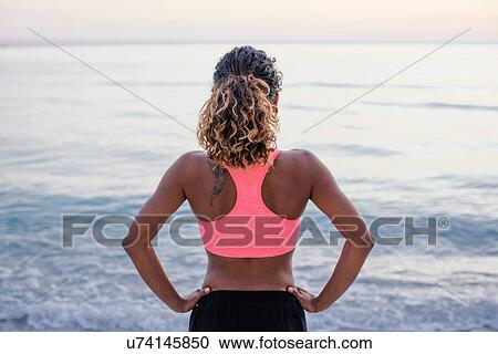 Rear view of young female runner taking a break on beach, Tuscany, Italy View Large Photo Image Stock Image - Rear view of young female runner taking a break on beach, Tuscany, Italy. Fotosearch