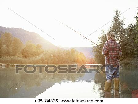Stock Photography - Rear view of young man fishing in lake, Premosello, Verbania, Piemonte, Italy. Fotosearch